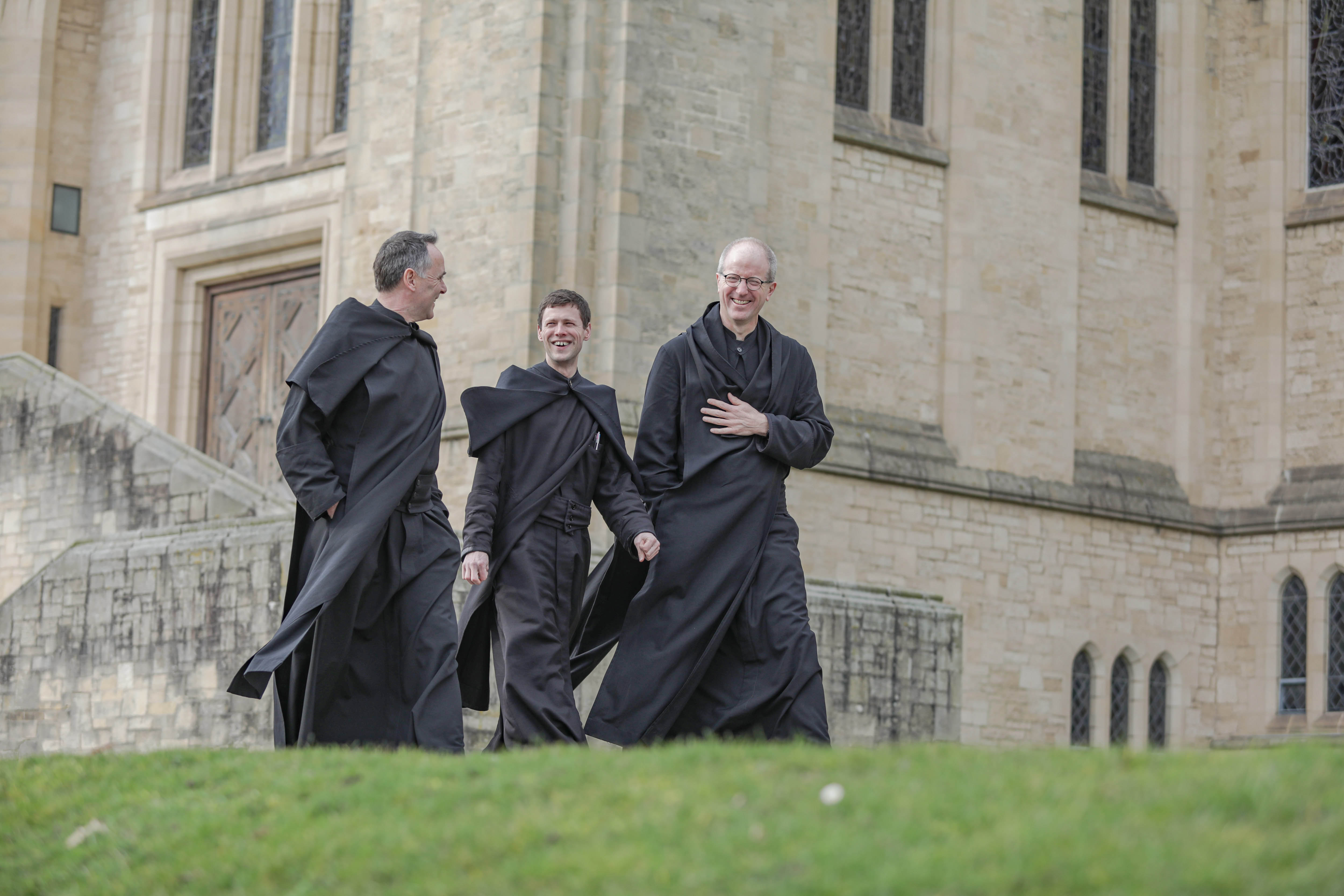 Three Ampleforth monks walking in front of the Abbey Church smiling