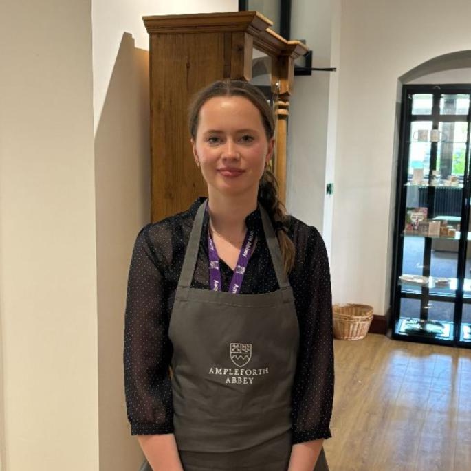 Woman with brown tied back hair wearing Ampleforth Abbey branded apron and uniform