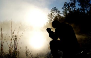 Man sat in prayer in the morning sun